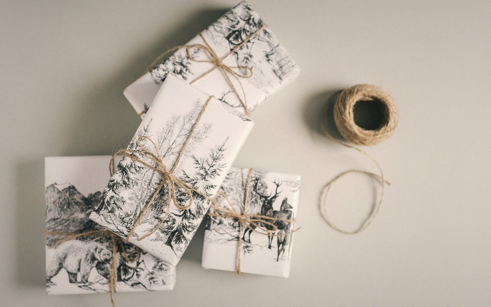 Gifts wrapped in wildlife-patterned paper tied with twine beside a ball of string