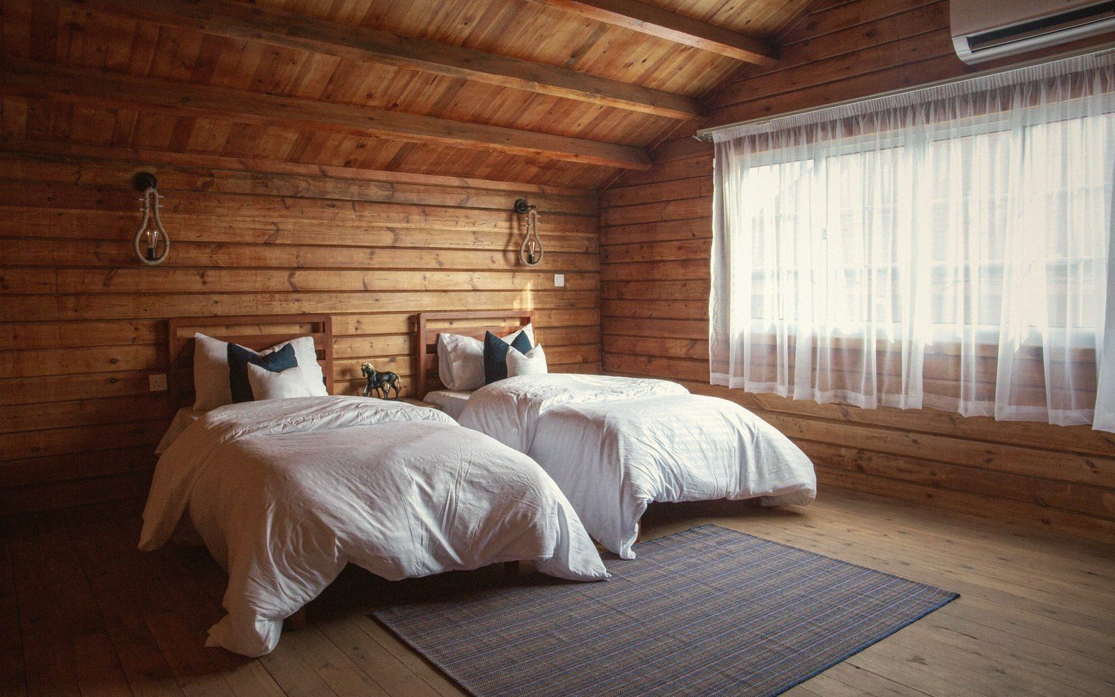 Two single beds with white linens in a wood-paneled cabin bedroom